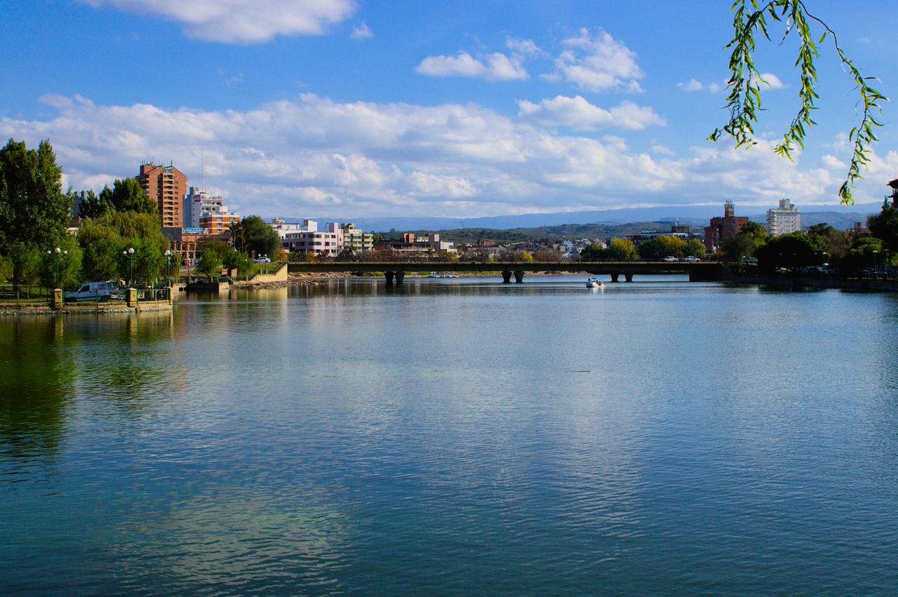 Cidade média diante de lago e serra ao fundo.