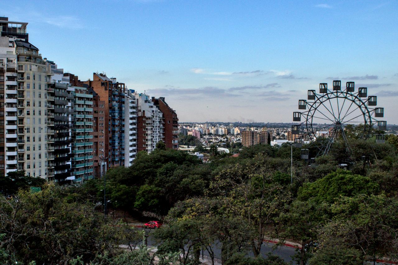 Edifícios, parque, roda gigante e província ao fundo.