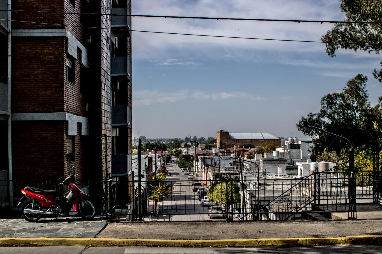 Vista para a província entre edifícios e casario térreo. Motocicleta vermelha à esquerda.