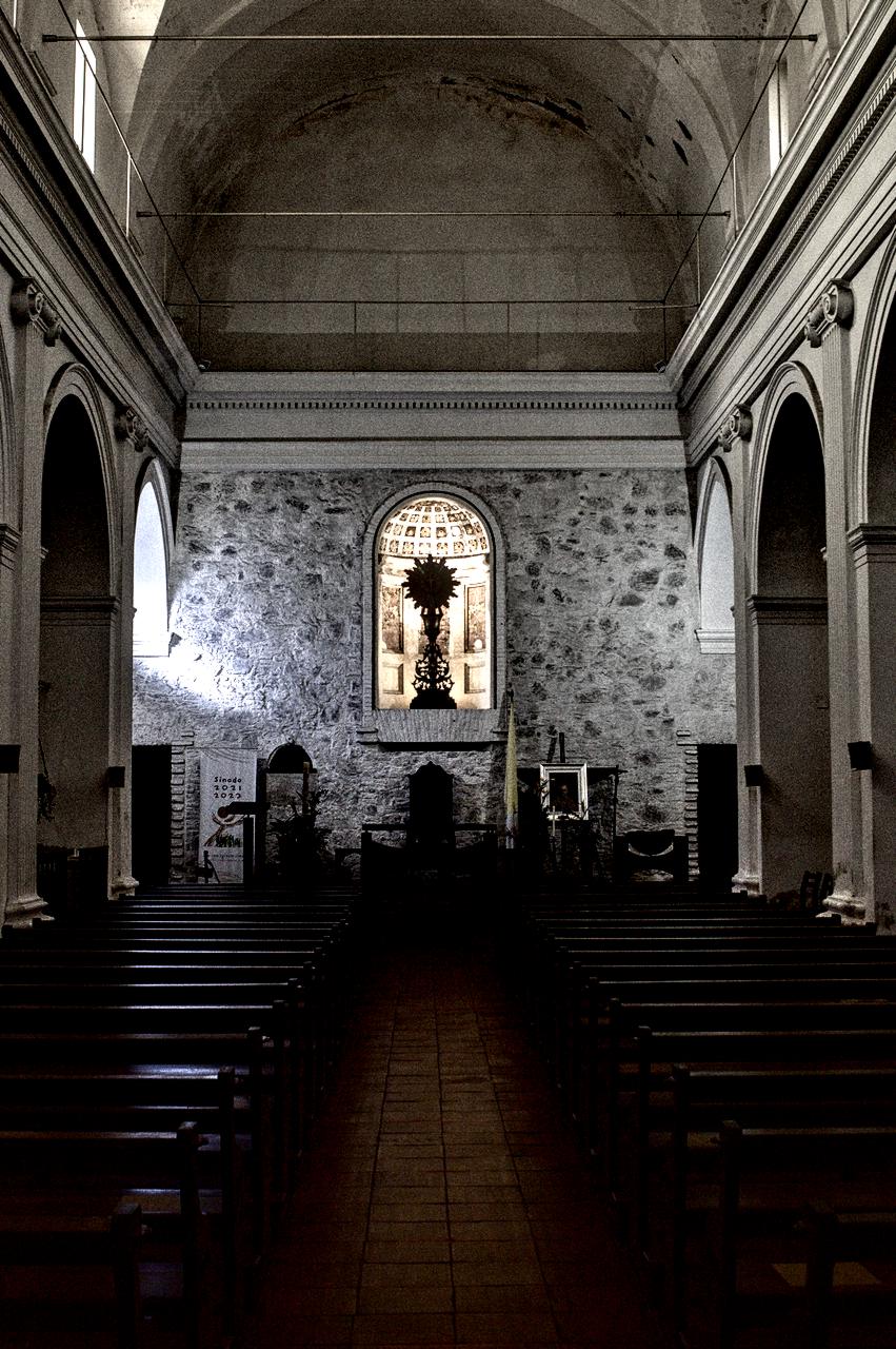 Interior de igreja antiga com bancos de madeira e Santíssimo Sacramento no altar.