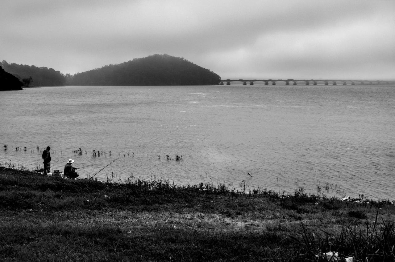 Homens pescando na orla do braço Bororé da Represa Billings