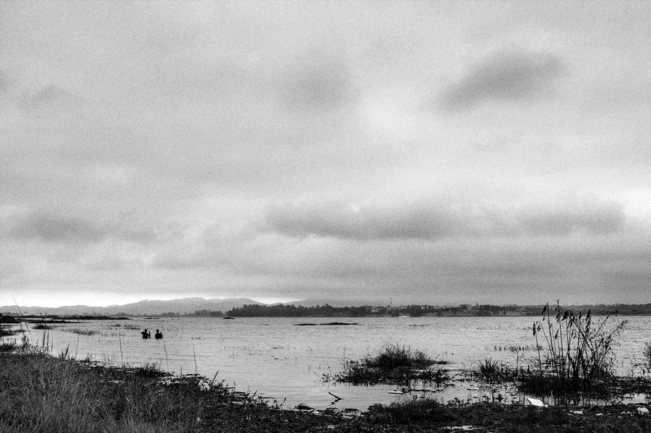 Represa Taiaçupeba coroada pela Serra do Itapety e homens pescando dentro d'água