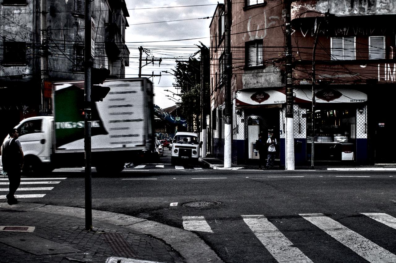 Travessia de pedestre e passagem de caminhão junto a edifícios baixos e antigos.