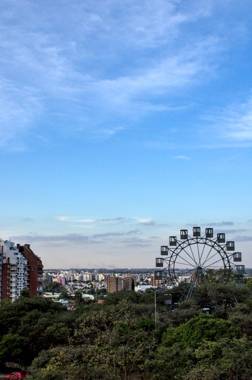 Edifícios, parque, roda gigante e província ao fundo.