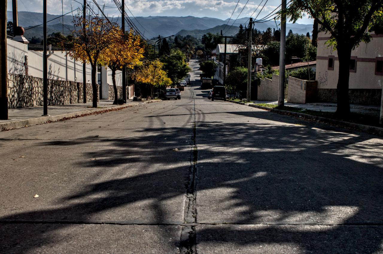 Rua suburbana em ladeira e serras da província ao fundo.