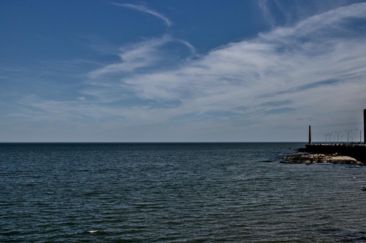 Chaminé à direita, mar predomina à esquerda sob o céu azul.