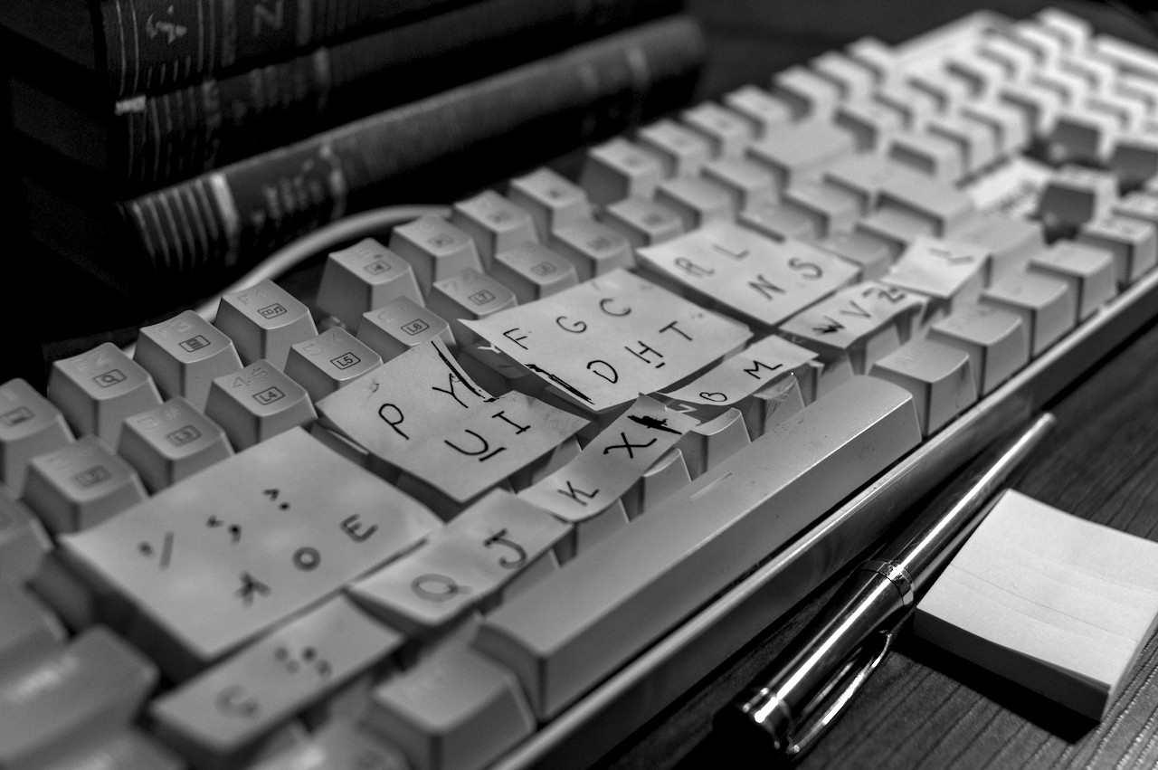Teclado branco coberto com papeis amarelos com outra disposição de letras.