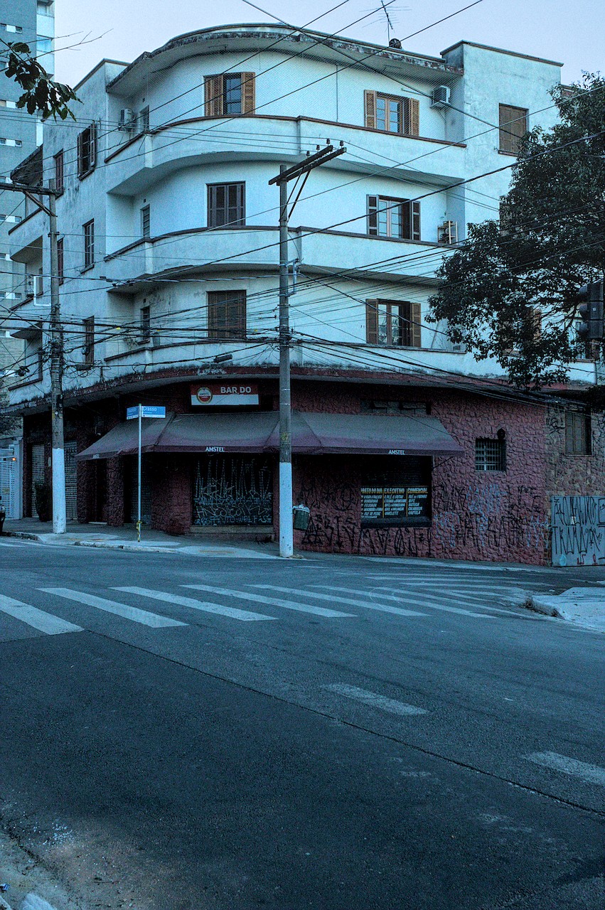 Edifício de esquina de três andares em cor clara.
