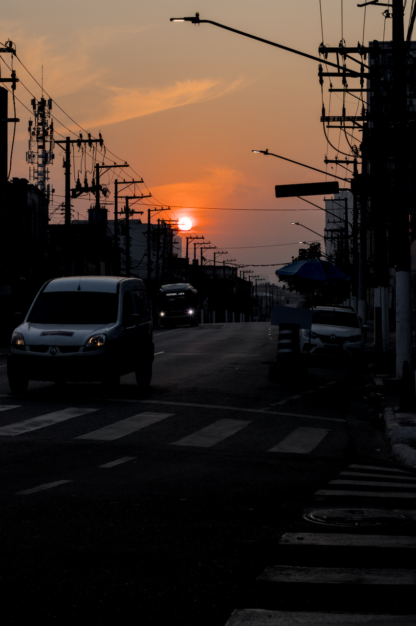 Alto contraste. Ambiente escuro e Sol no céu alaranjado de fim de tarde.