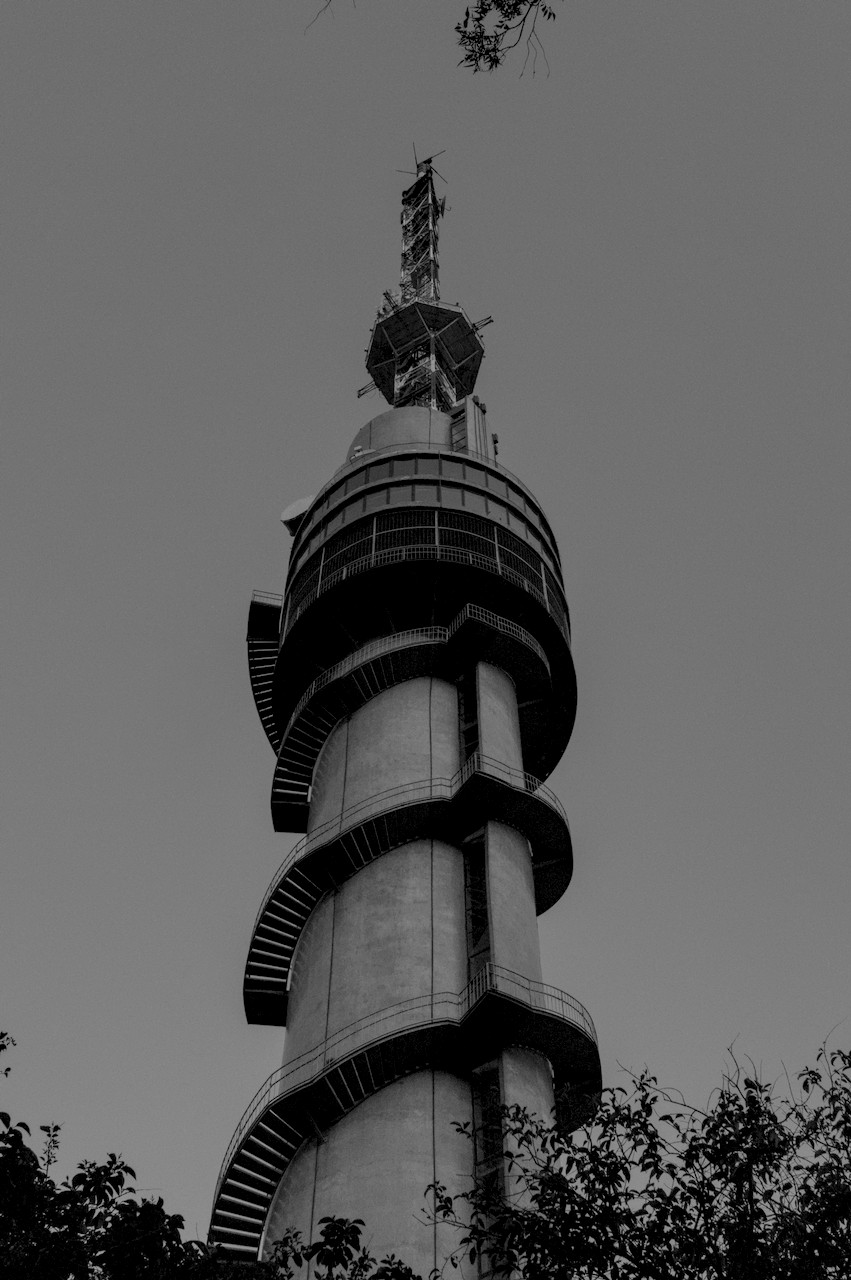 Contra-plongée de torre cilíndrica de concreto, vidro e metal com escadas ao redor.