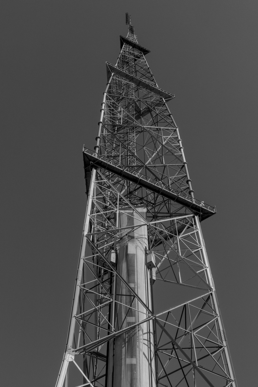 Contra-plongée de torre metálica com estrutura de concreto cilíndrica no centro.