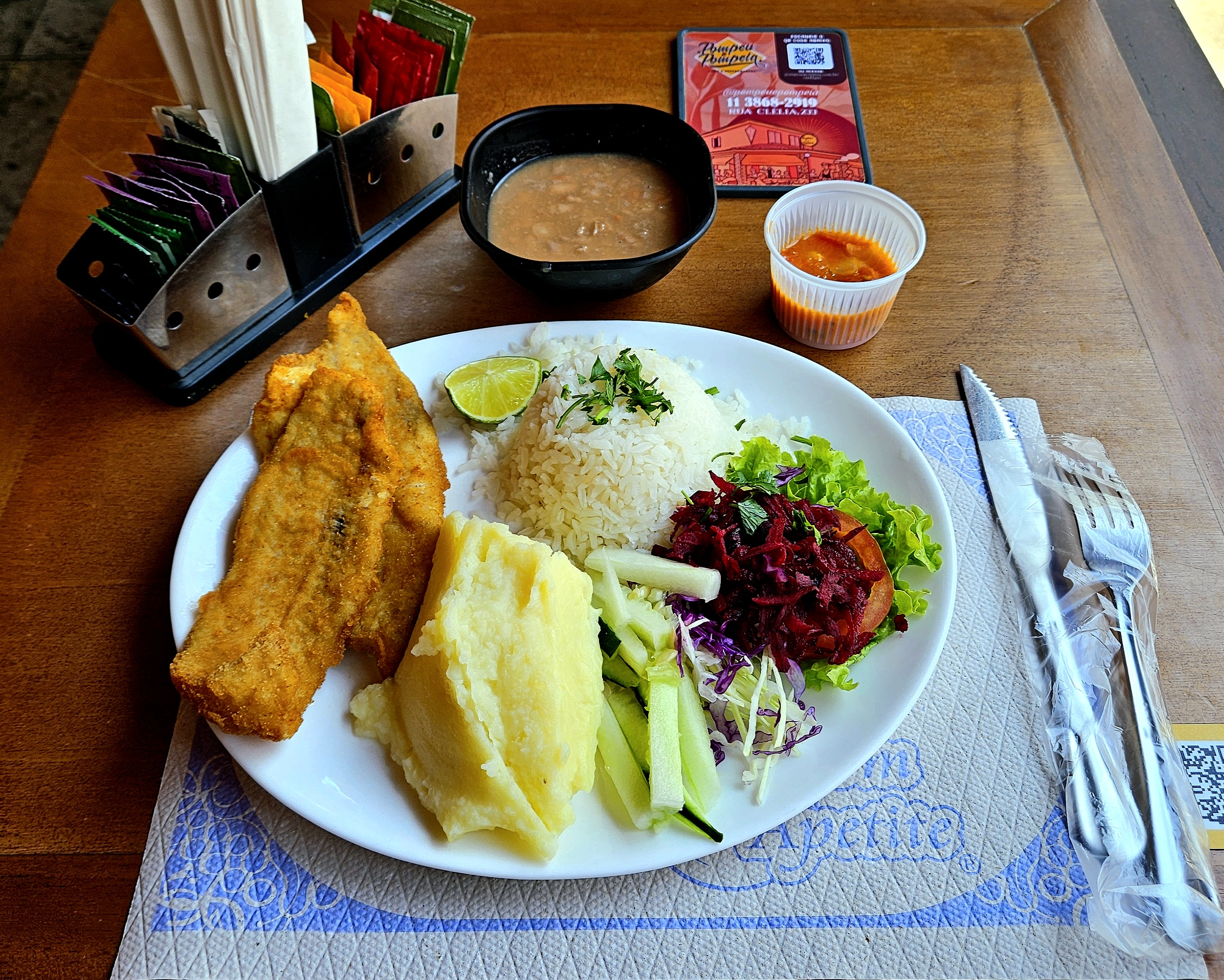 Pato com peixe empanado, purê, arroz com cheiro verde e salada; guia de feijão e copinho com molho.